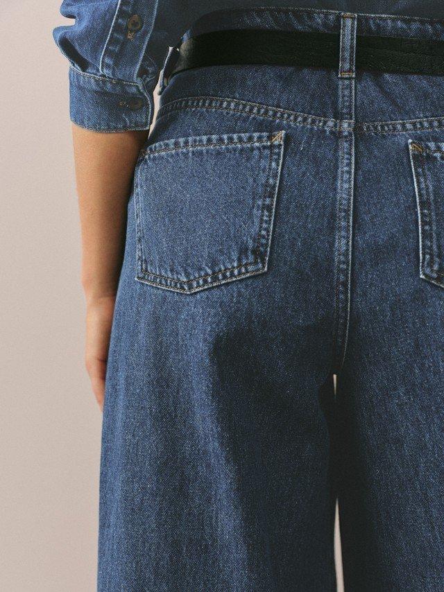 a person wearing a pair of blue jeans with a belt