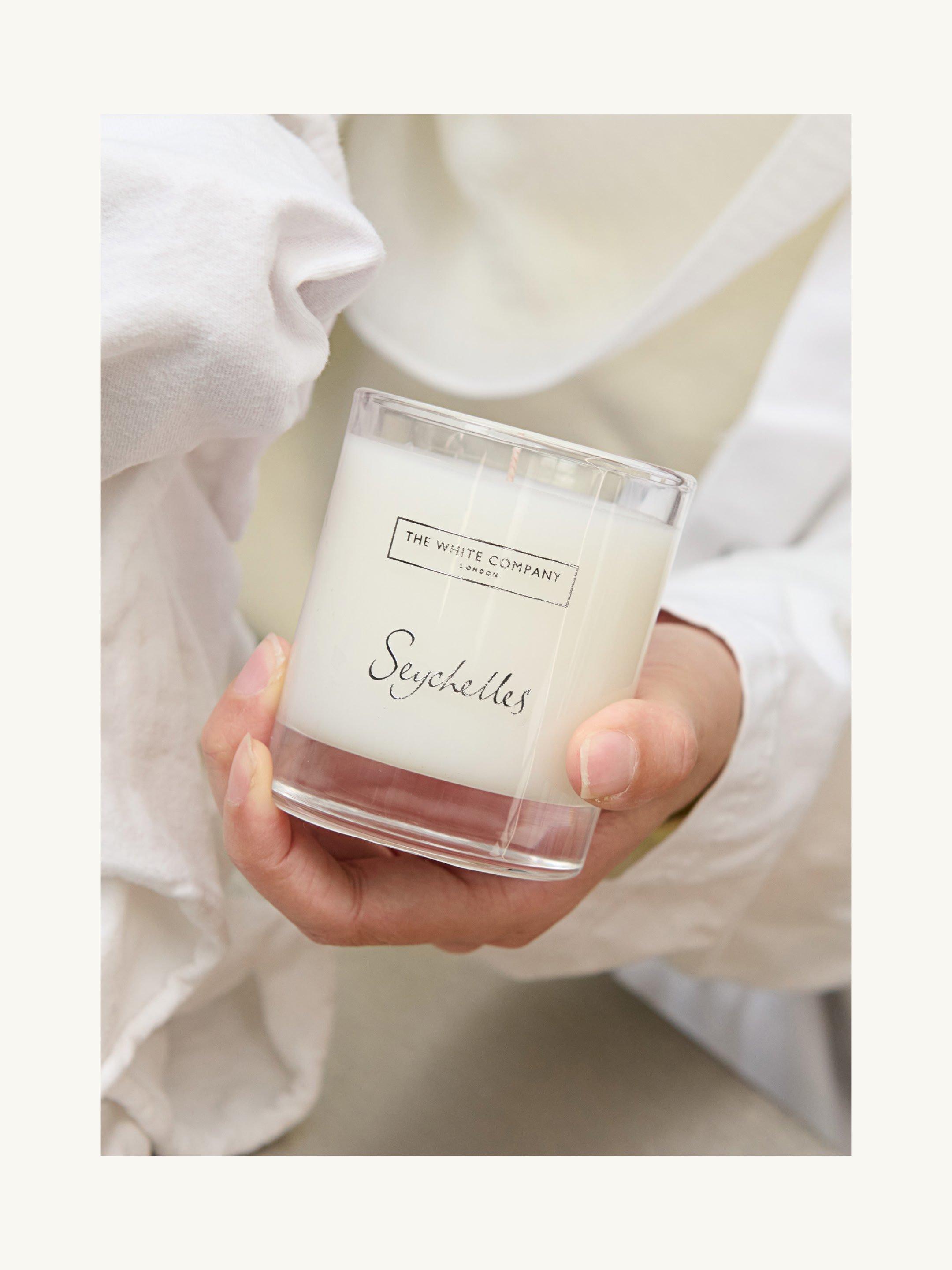 a person holding a candle in their hand with a white cloth