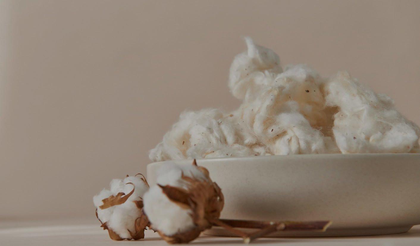 a bowl of cotton in a beige bowl on a table
