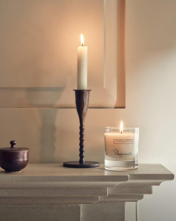 a candle and a small pot sit on a mantle