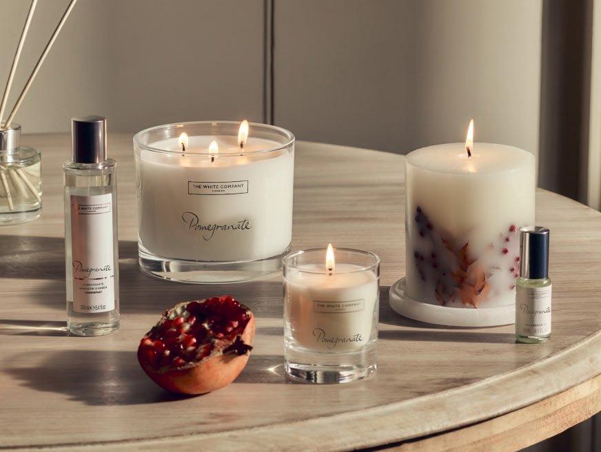 a table with candles and perfumes on it and a pomegranate