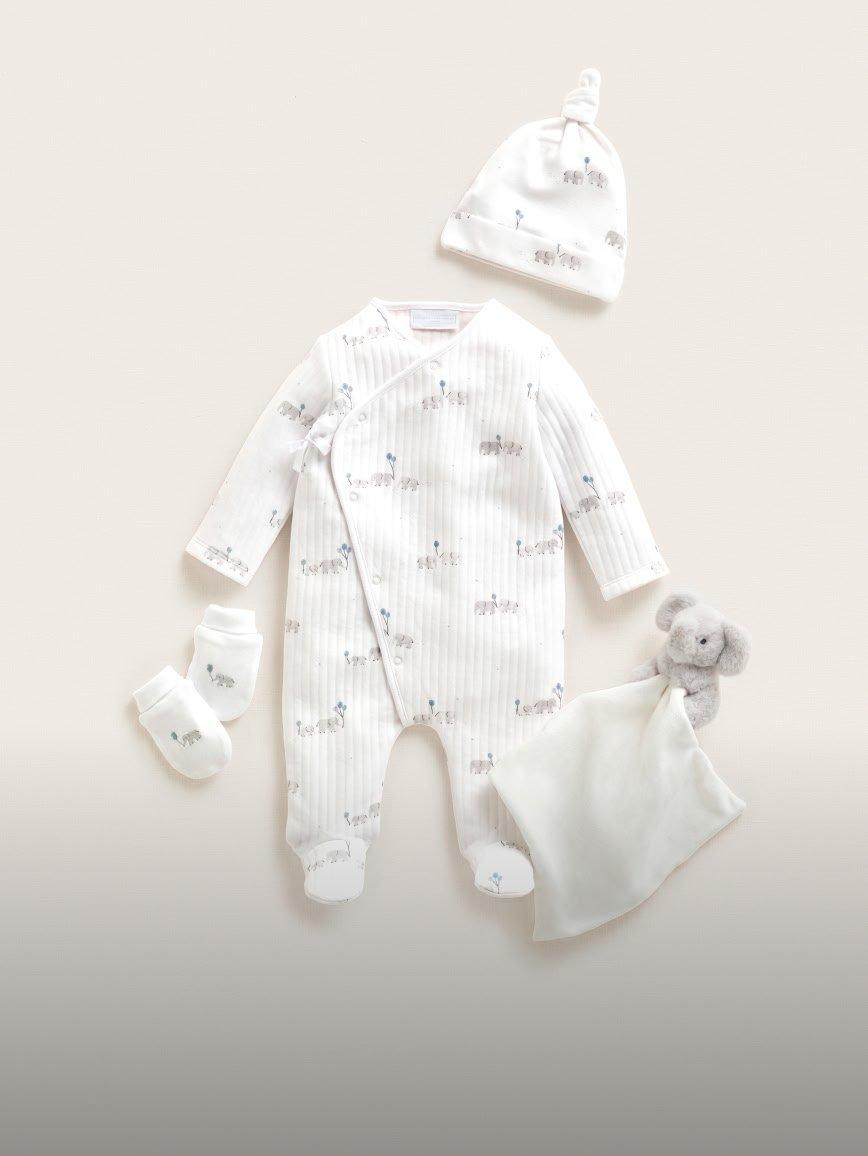 a baby's white outfit with a hat, socks, and a stuffed animal