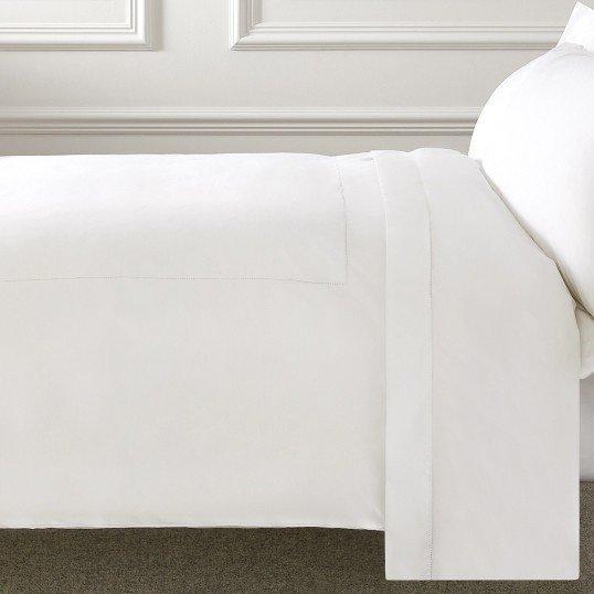 a white bed with a white comforter and pillows