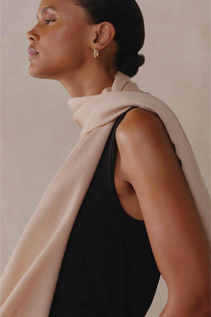 a woman wearing a black top and a tan scarf