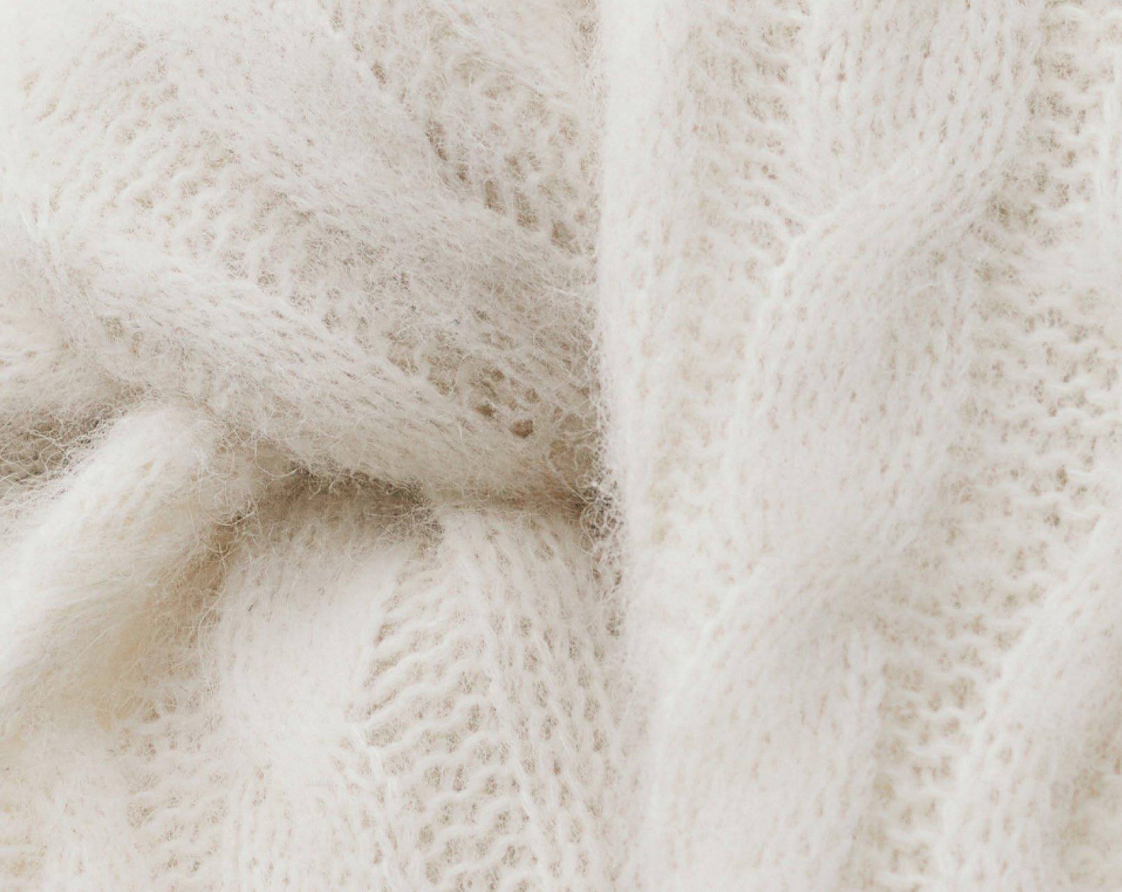 a close up of a white sweater with a knot in it