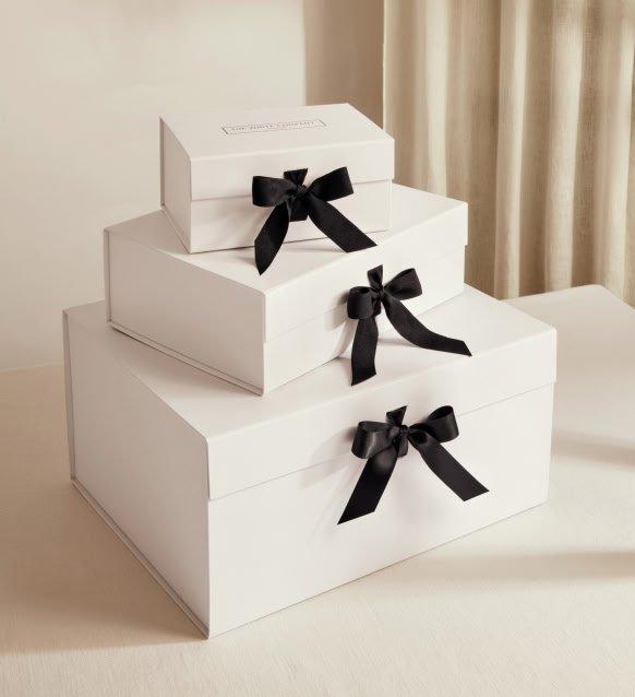 three white boxes with black bows sitting on top of a table