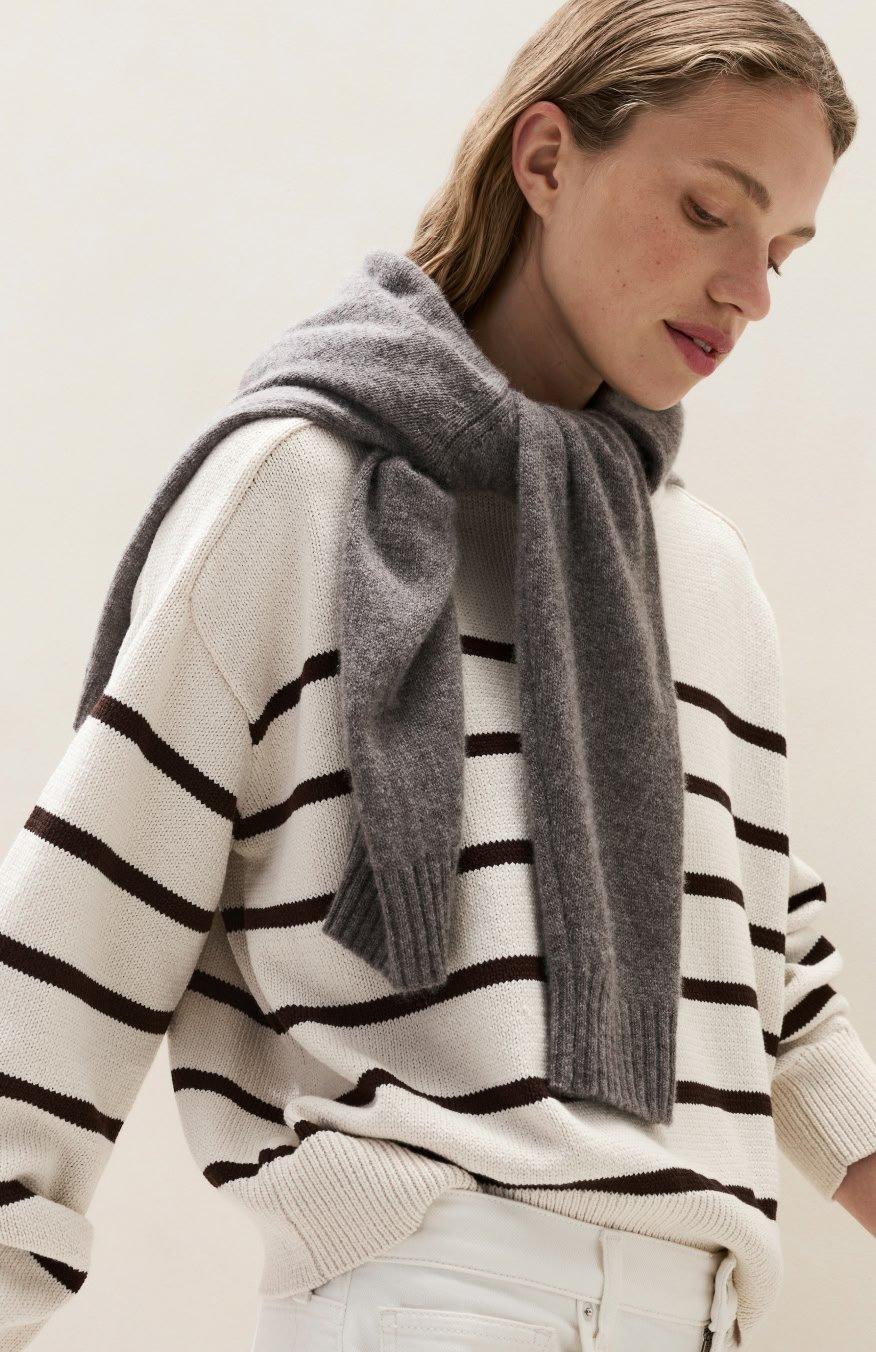a woman in a striped sweater and scarf looking down