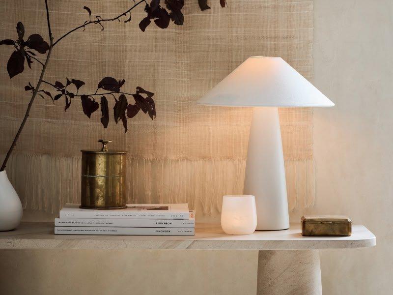 a table with a lamp, books, and a candle on it
