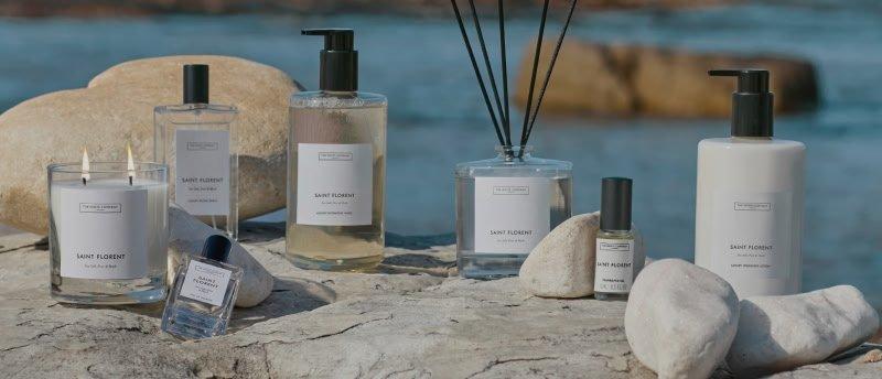 a group of bottles of perfume and candles sit on a rock