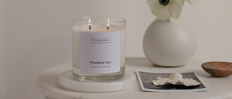 a candle on a small table next to a vase and a picture