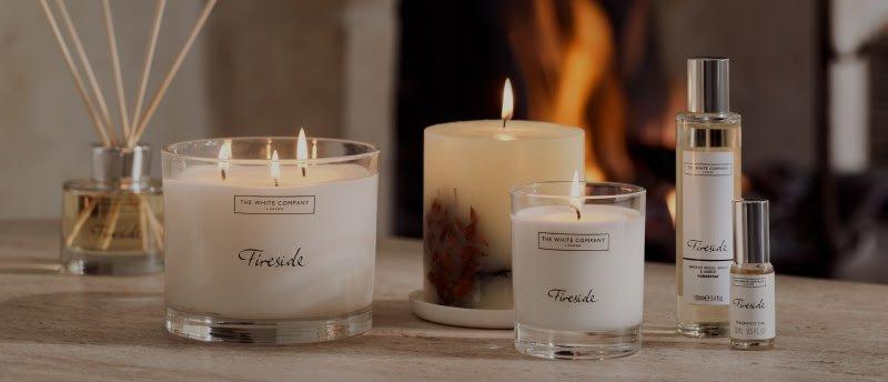 a group of candles sit on a table next to a fireplace