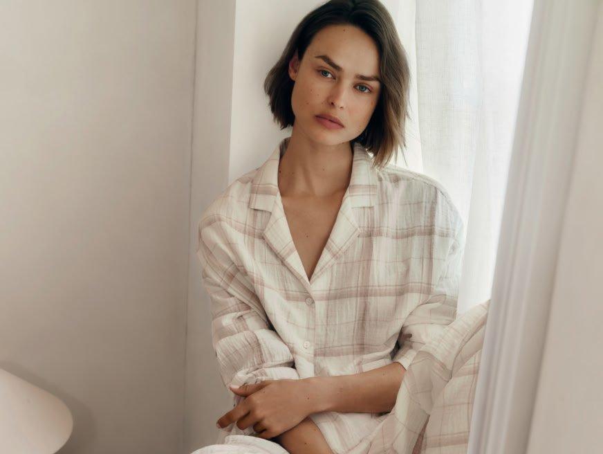 a woman in pajamas leaning against a window sill