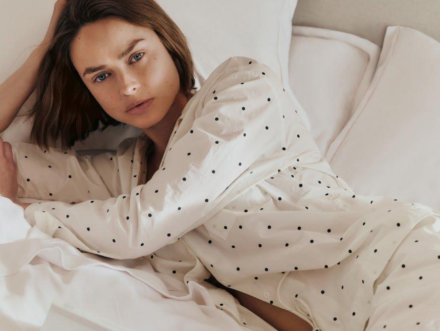 a woman laying on a bed in a white pajama set