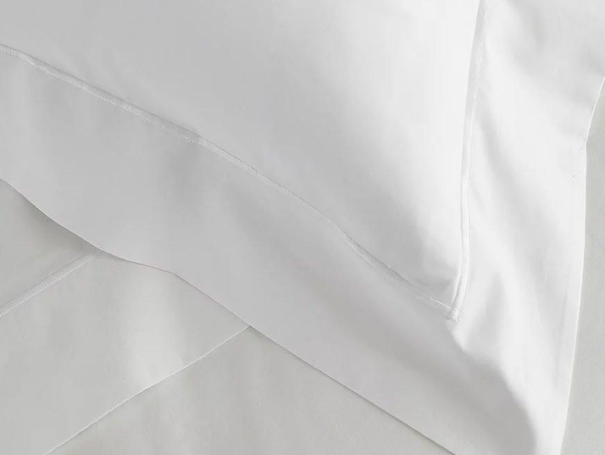 a close up of a white bed with a white comforter
