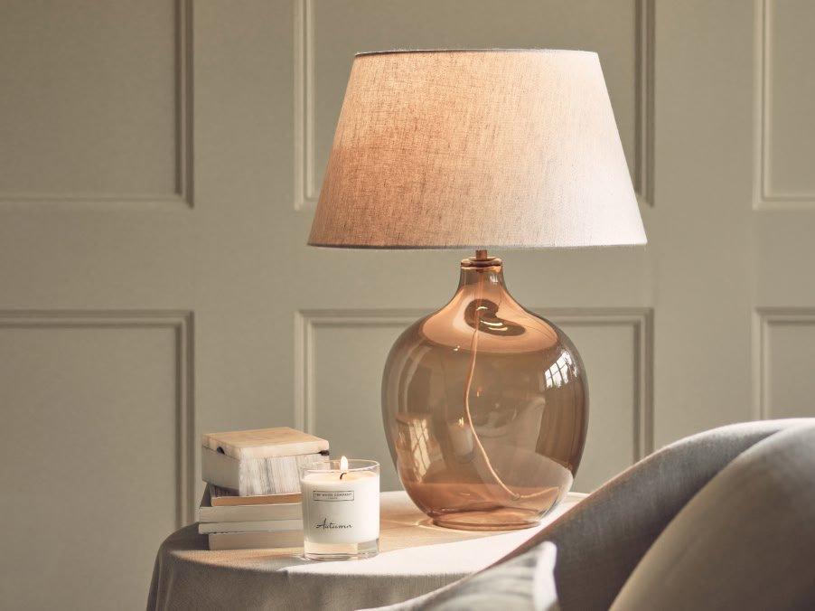 a table with a lamp and a book on it next to a chair