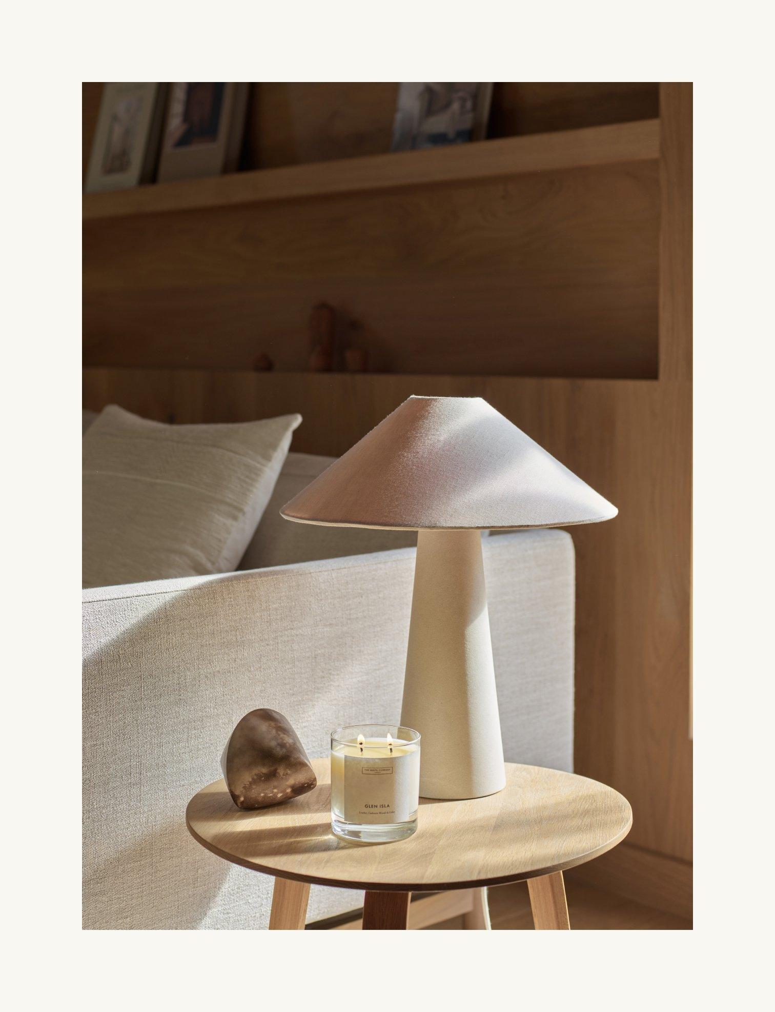 white lamp on a table with a candle