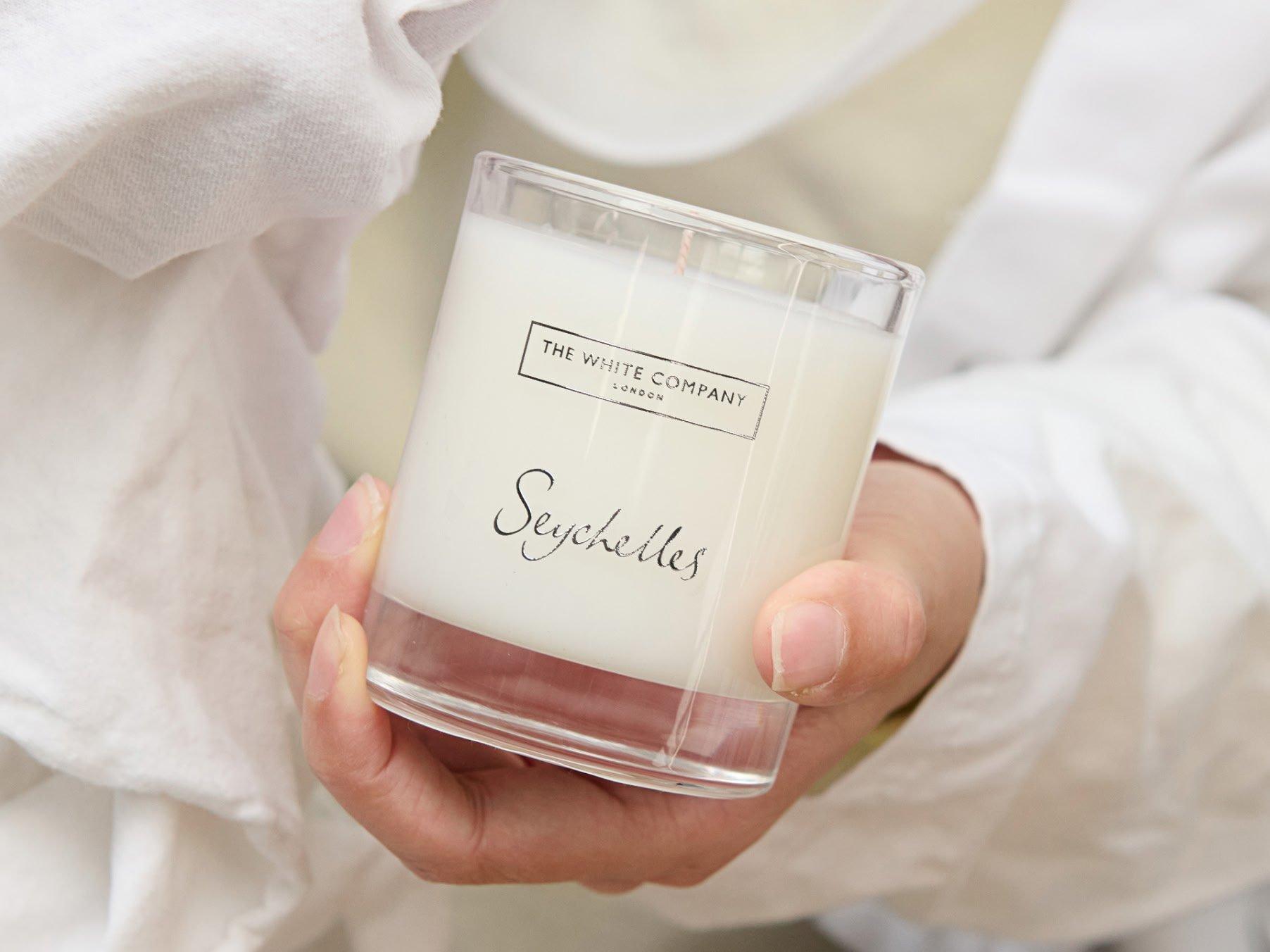 a person holding a candle in a white robe
