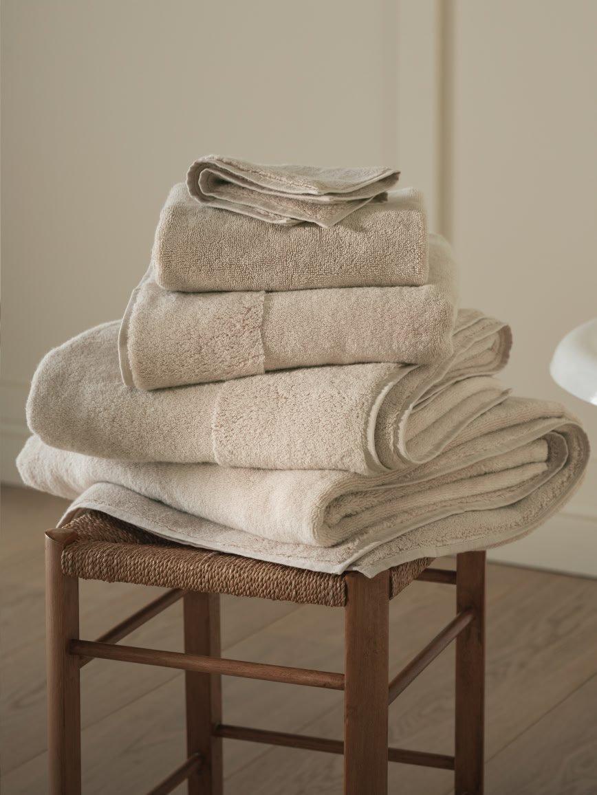 a stack of white towels sitting on a stool next to a bathtub