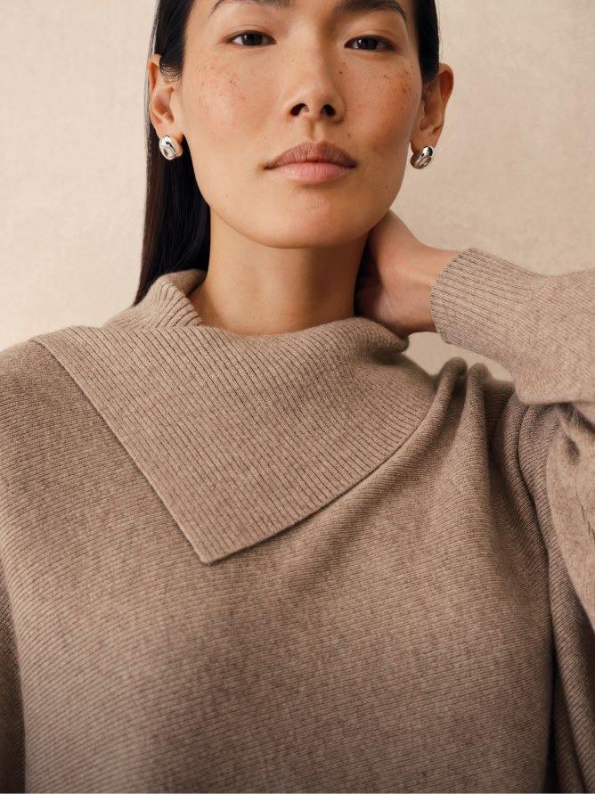 a woman with a sweater on her head and earrings
