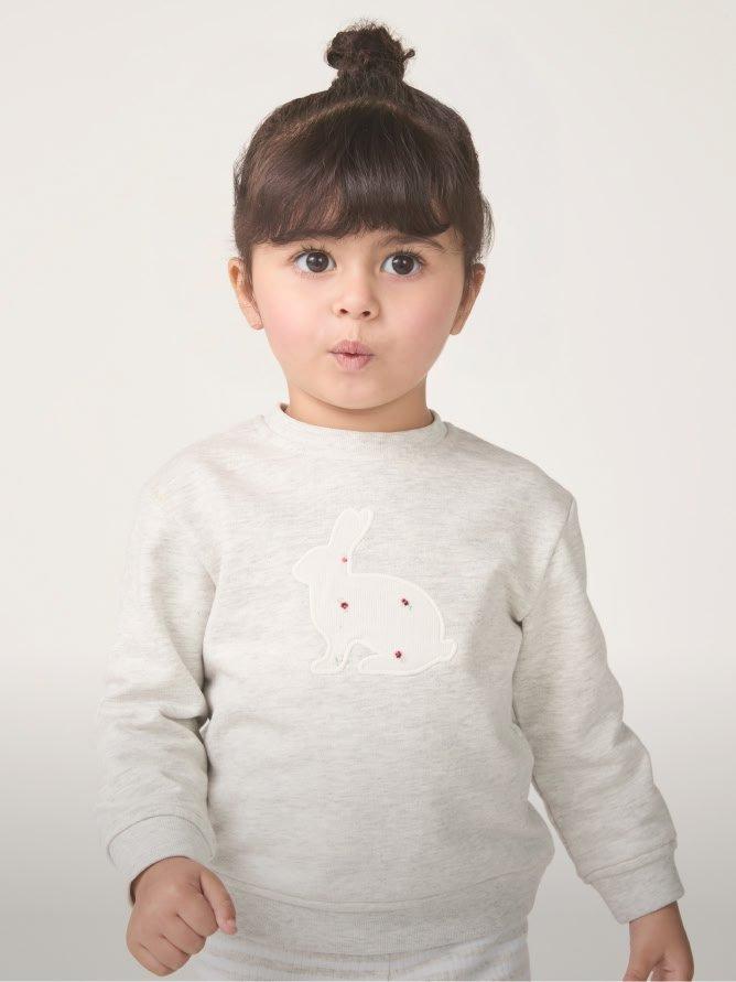 a little girl in a white sweatshirt and black pants